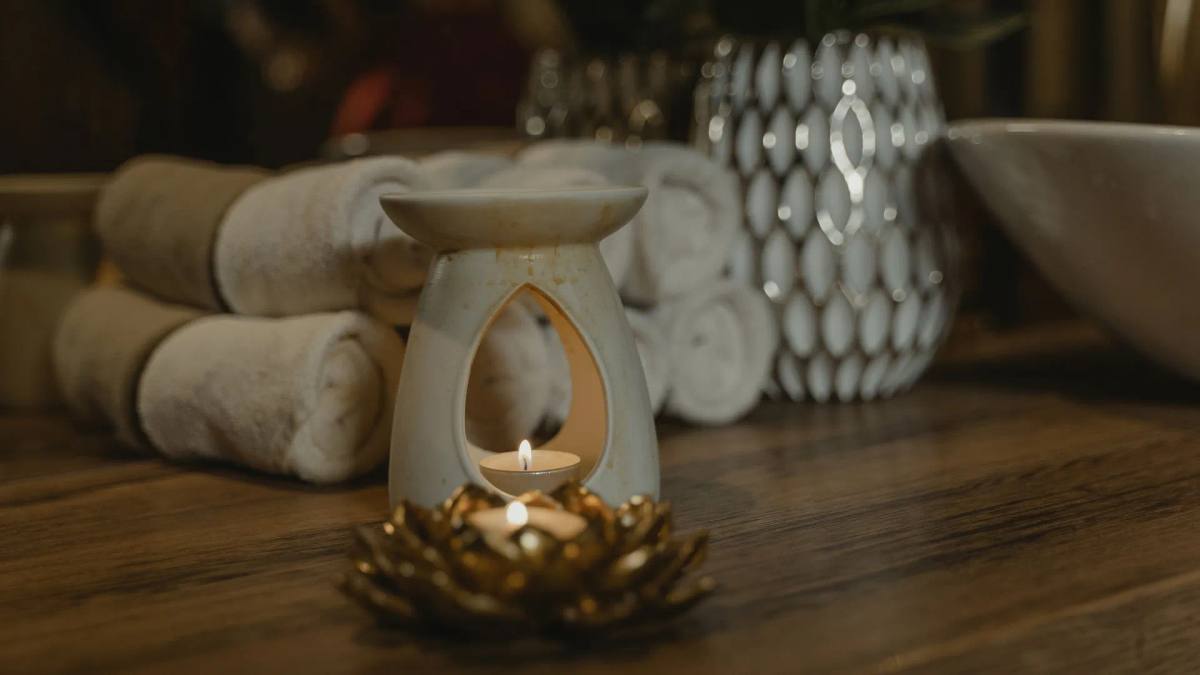 Aromalampa se svíčkou a složené ručníky v klidném salonu